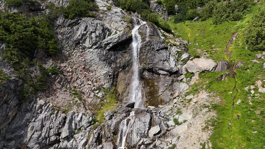 Powerful Waterfall Plunging Down Mountainous Landscape with Snow Patches, British Columbia, Canada