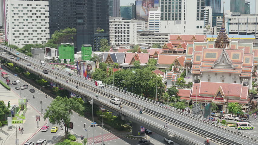 Bangkok, Thailand - 4 July, 2025: Aerial view of city roads and scenic tile roofs of a Buddhist temple in downtown. Amazing cityscape. Bangkok is a popular tourist destination of Asia.