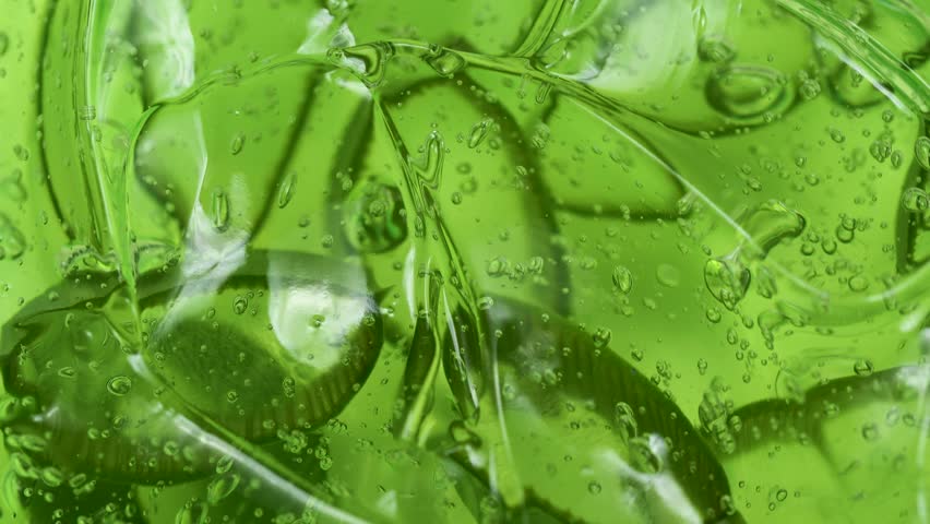 Serum gel texture with aloe vera leaf slices, green transparent cream background