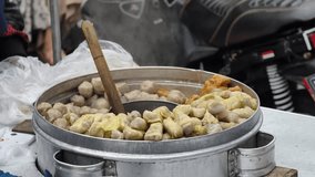 Close-up of a large metal pot filled with steaming meatballs, a wooden spoon stirring them, and a hand reaching in. - Powered by Shutterstock - Get 15% off with code: PIKWIZARD15