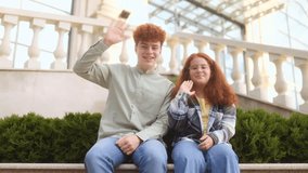 Teenage siblings with red hair wave their hands while sitting outdoors. Casual clothes, natural setting, and simple greeting gesture highlight a lifestyle and youth portrait. - Powered by Shutterstock - Get 15% off with code: PIKWIZARD15
