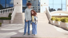 Two teenage siblings with curly red hair share a warm hug outdoors. The brother gently holds his sister on the steps of a modern building, radiating closeness and love. - Powered by Shutterstock - Get 15% off with code: PIKWIZARD15