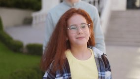 Redhead girl with glasses stands outdoors smiling confidently, wearing casual plaid shirt and yellow t-shirt, looking calm and cheerful in natural daylight. - Powered by Shutterstock - Get 15% off with code: PIKWIZARD15
