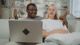 Happy interracial loving couple using laptop at home, choosing apartment or trip. Portrait of african american man embracing his beautiful blonde girlfriend when viewing pictures at computer screen - Powered by Shutterstock - Get 15% off with code: PIKWIZARD15