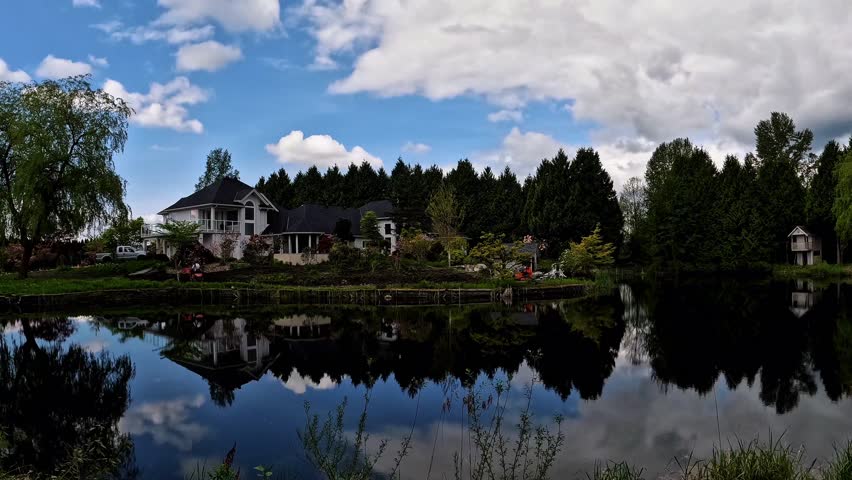 An excavator working in the backyard of a beautiful lakeside house, leveling the landscape for garden construction under clear blue sky. Peaceful waterfront property development scene.