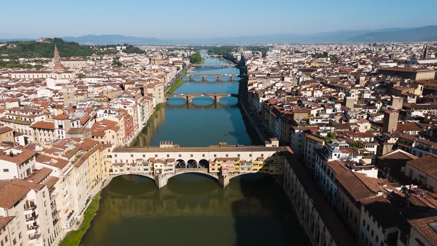 Aerial view of Ponte Vecchio at sunrise — calm river reflections and the city slowly awakening