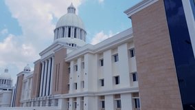 Smooth vertical pan shot revealing the modern, classical-inspired facade of a multi-story corporate, institutional, or university building with white pillars and stone accents. - Powered by Shutterstock - Get 15% off with code: PIKWIZARD15