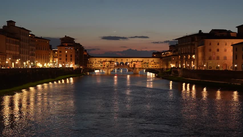 Night view of Ponte Vecchio, its warm lights reflecting softly across the Arno River.