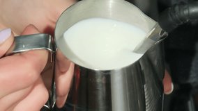 Barista holds metal pitcher in hands filling vessel with milk. Stream of liquid passes from coffee machine through steam wand slow motion - Powered by Shutterstock - Get 15% off with code: PIKWIZARD15