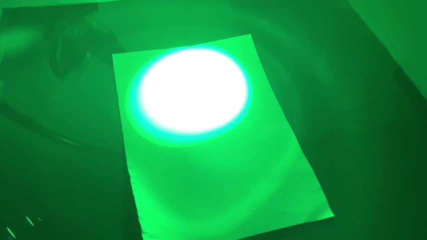 Scientist checking a luminescent handprint on a phosphorescent screen
