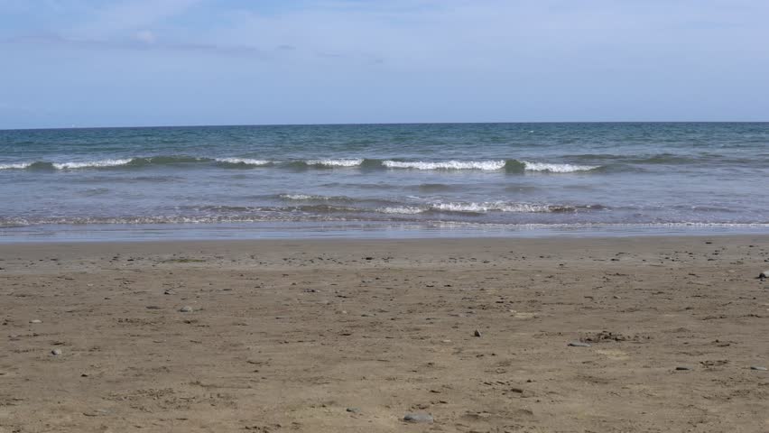 Seashore, sand and the movement of small waves - relaxation.
