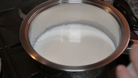 Pouring sugar into milk in a saucepan, close-up of cooking process in a home kitchen. - Powered by Shutterstock - Get 15% off with code: PIKWIZARD15