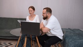 Business partners working from home are sitting at a glass table, woman holding documents and discussing with a man looking at laptop, having a video call - Powered by Shutterstock - Get 15% off with code: PIKWIZARD15