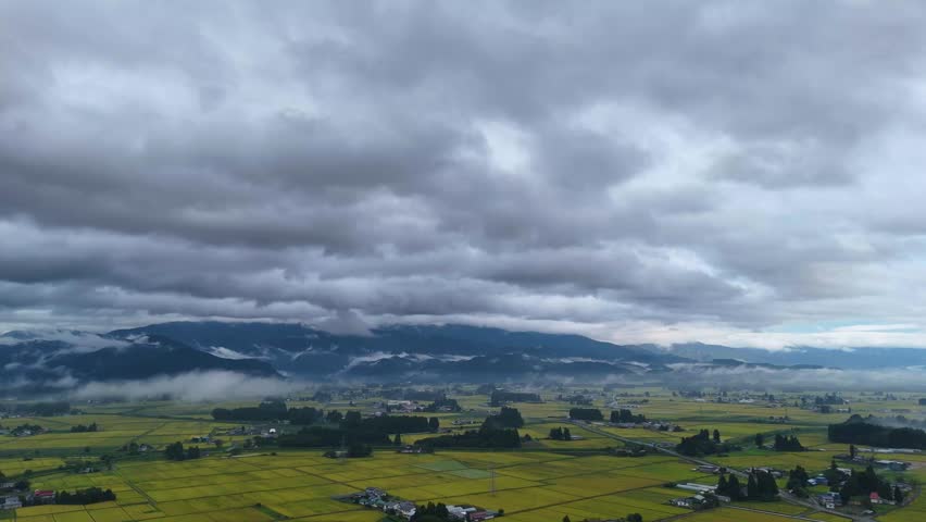 Aerial view of a rural landscape in Tohoku with fog forming near the ground in the early autumn morning.