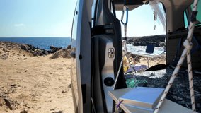 Mature freelancer working on a laptop from his camper van parked on a volcanic beach, embracing the digital nomad lifestyle and remote work freedom on a sunny day by the ocean - Powered by Shutterstock - Get 15% off with code: PIKWIZARD15