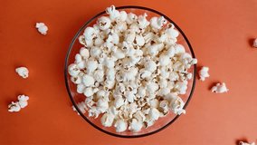 Overhead ultra slow motion shot of popcorn filling bowl on orange background, emphasizing motion, pattern, and appetizing color texture - Powered by Shutterstock - Get 15% off with code: PIKWIZARD15