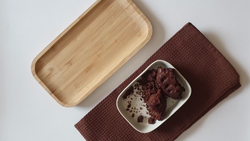 Hand Placing Chocolate Fruit Cake Slice on White Plate	