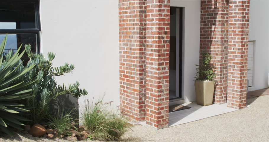 Happy couple walking together, holding hands, smiling, looking at house and embracing on a sunny day. moving house, relationship and lifestyle concept.