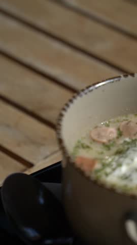 Frankfurt soup with sausage, sour cream, and parsley sprinkled on a plate.