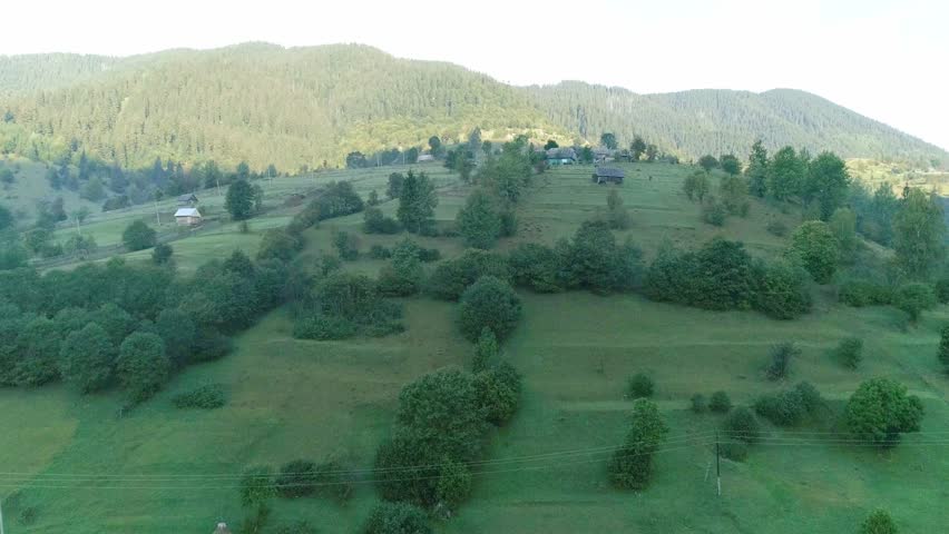 Green grass hill in morning sunlight and mountain around, morning sunlight illuminates green grassy hill surrounded by mountains. serene landscape with peaceful atmosphere ideal for nature themes