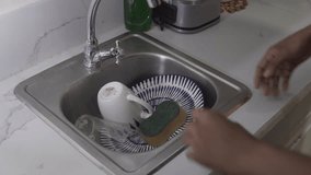 Adult man washing dishes with a sponge and water in a stainless steel kitchen sink - Powered by Shutterstock - Get 15% off with code: PIKWIZARD15
