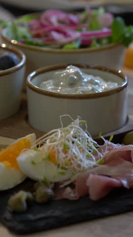 A delicious cold plate with eggs, sausage, olives, ham, cheese, vegetables, and bread.