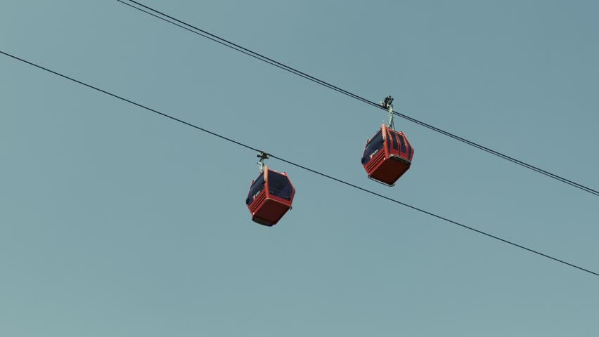 Nanjing, China. Aerial view of red cable cars suspended in midair against a clear blue sky.