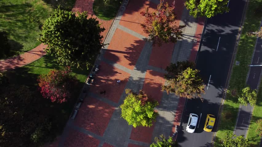 High-altitude drone shot of a green urban park surrounded by residential areas in Bogotá, Colombia. Trees, walkways and streets are visible on a sunny day.