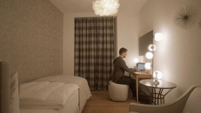 Man working on laptop in cozy modern hotel room at night. Concept of remote work, digital nomad lifestyle, and business travel in comfortable accommodation with warm light - Powered by Shutterstock - Get 15% off with code: PIKWIZARD15