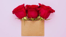 A top view animation of three bright red rose flowers in a brown craft envelope with copy space, creating a trendy banner for Valentine's Day, International Women's Day, or Mother's Day celebrations - Powered by Shutterstock - Get 15% off with code: PIKWIZARD15