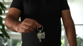 A person is holding keys with a house keychain. The background is blurred, suggesting an indoor setting. The lighting is bright, indicating it is daytime. This could be a real estate deal. - Powered by Shutterstock - Get 15% off with code: PIKWIZARD15