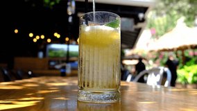 A refreshing beverage is poured into a tall glass on a wooden table. The sunlight shines, highlighting the fizzy drink in an outdoor setting. Perfect for summer! - Powered by Shutterstock - Get 15% off with code: PIKWIZARD15