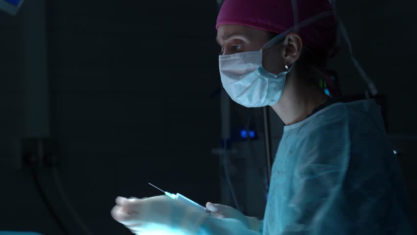 Professional female surgeon in sterile gown and mask performing a delicate and precise surgical procedure on a patient in a dark, modern operating theater, illuminated by a surgical lamp - Powered by Shutterstock - Get 15% off with code: PIKWIZARD15