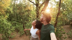 Happy multiracial boyfriend and girlfriend walking and talking in a lush green forest. Point of view video of a couple enjoying nature - Powered by Shutterstock - Get 15% off with code: PIKWIZARD15