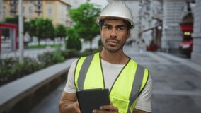 Man engineer tapping tablet on street in white tshirt and neon vest; concentration planning productivity efficiency. - Powered by Shutterstock - Get 15% off with code: PIKWIZARD15