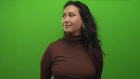 Young hispanic woman with hand cupping ear for listening in green studio; curiosity listening attention. - Powered by Shutterstock - Get 15% off with code: PIKWIZARD15