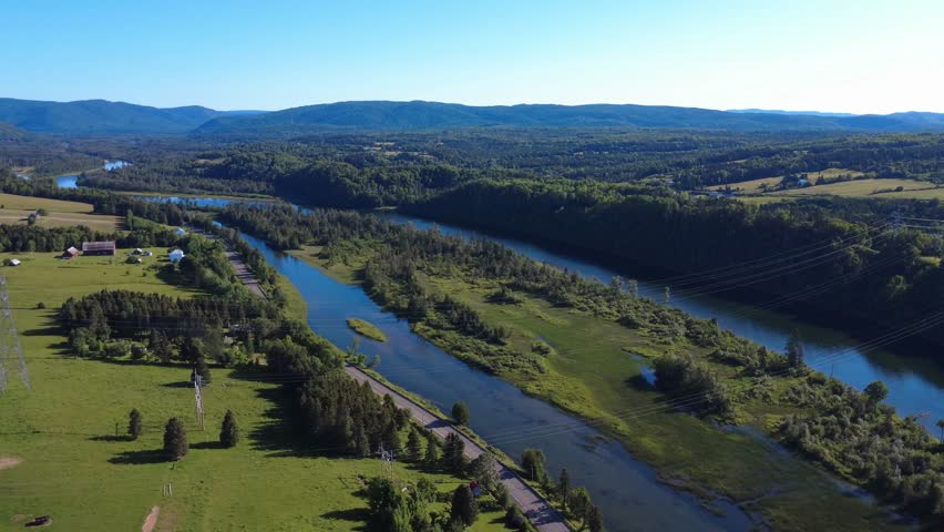 Three power transmission lines cross the Cascapedia River, a salmon fishing river that splits into two branches at this point. Gaspé Peninsula, Quebec, Canada, 2025.