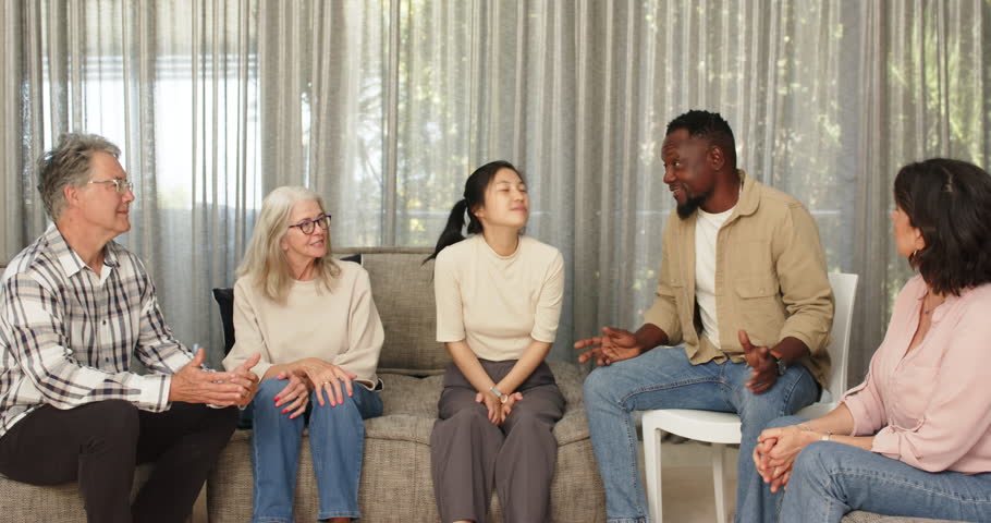 Happy male therapist handing statue to patient, with patients in group therapy . Teamwork, mental health, communication and therapy concept.