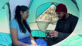 Man and woman sitting inside their camping tent in a forest, smiling as they review photos on a digital camera. A warm and relaxed moment that captures the joy of outdoor adventures and togetherness i - Powered by Shutterstock - Get 15% off with code: PIKWIZARD15