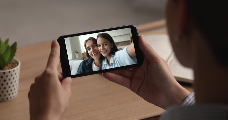 Female hold smartphone, kid and mom displayed on device screen, making selfie, engage in videoconference call use application. Social media platform user, videocall between relatives people, close up