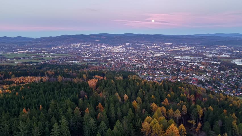 mountain ridge gazing at glowing city lights, serene evening scene with moon rising over dense woods