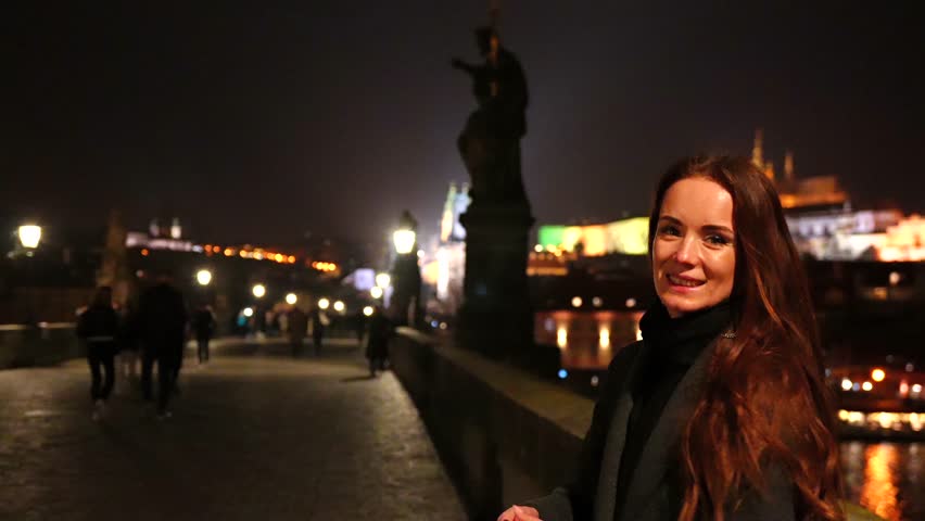 Prague Czech Republic, woman tossing coin into river at night