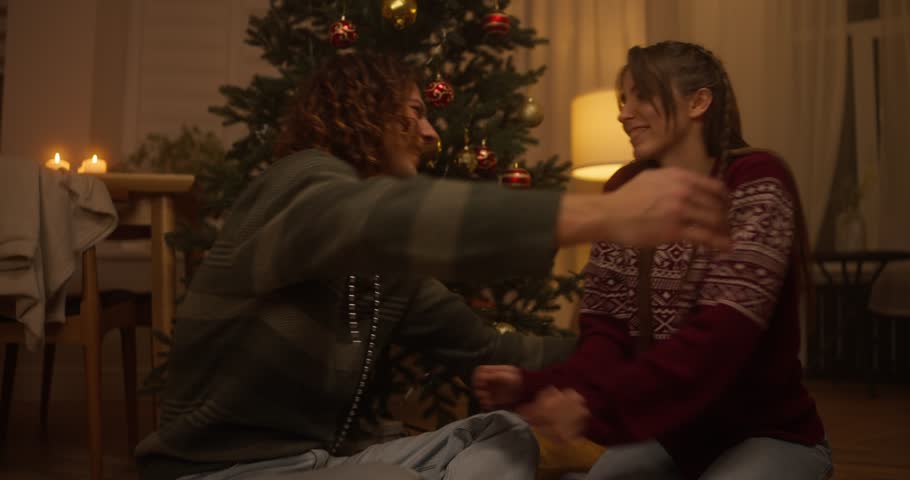 Cozy holiday hug shared between friends in a warm, festive living room setting