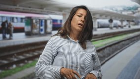 Woman points finger to wrist beside train tracks at station building platform; impatience waiting commute. - Powered by Shutterstock - Get 15% off with code: PIKWIZARD15