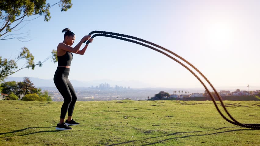 Mixed ethnicity (Asian-African) woman exercising in the park. The Los Angles skyline can be seen in the distance.
