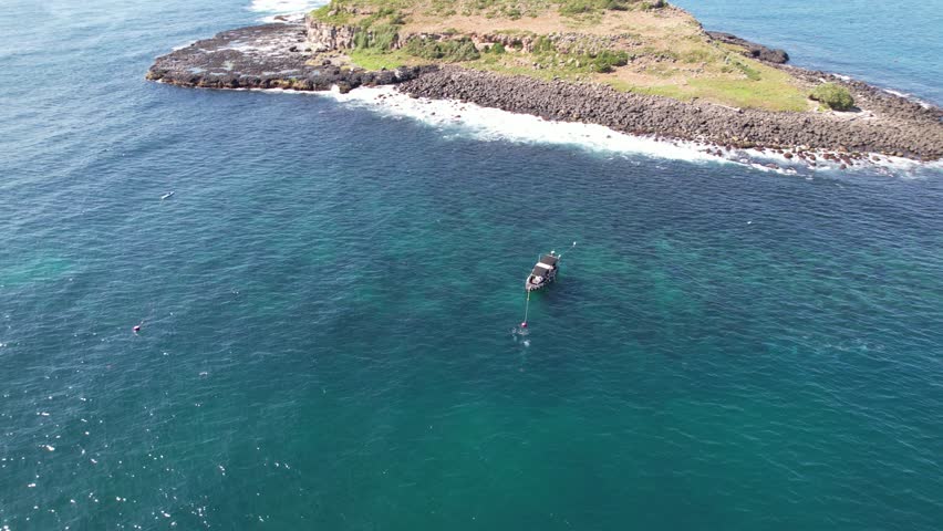 Elevated view of small tourist boat between Cook Island and Fingal Head causeway, northern New South Wales, Australia