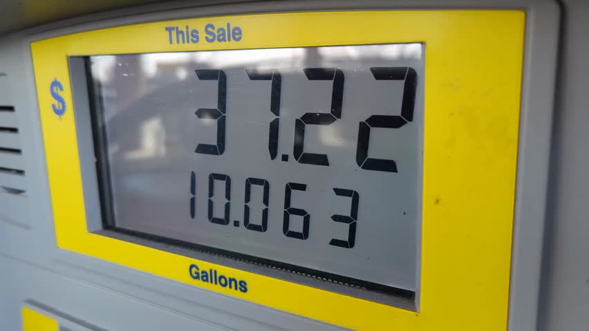 Gasoline price counter on digital display at night showing high fuel prices, reflecting inflation, rising costs, and economic impact in the USA.