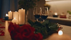 Close-up of two wine glasses on a kitchen table surrounded by burning candles and red roses, creating a cozy, romantic atmosphere perfect for Valentine’s or anniversary. - Powered by Shutterstock - Get 15% off with code: PIKWIZARD15