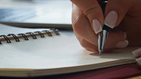 Close-up of a businesswoman’s hands writing in a notebook with a black pen, making notes at a modern office desk. - Powered by Shutterstock - Get 15% off with code: PIKWIZARD15