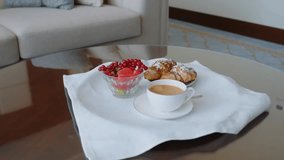 Medium close-up of manager’s hands serving breakfast with coffee, croissants, and fruit on table while preparing room for guest. - Powered by Shutterstock - Get 15% off with code: PIKWIZARD15